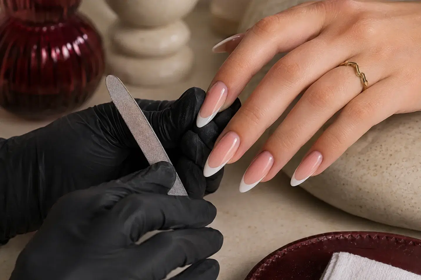 Een nagelstylist vijlt lange amandelvormige gelverlengingen met witte French tips.